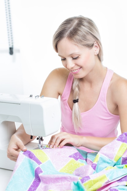 Hermosa mujer joven en la máquina de coser