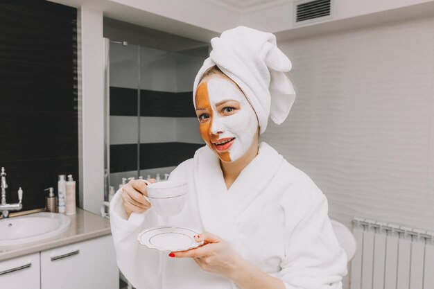 Hermosa mujer joven con mascarilla bebe café en la oficina de esteticistas