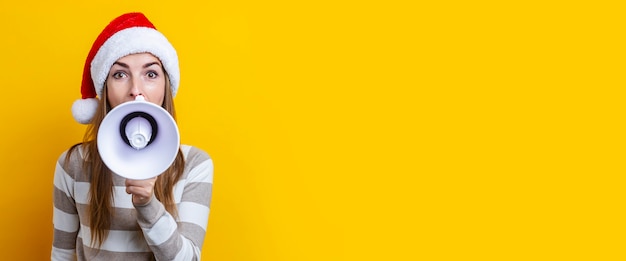 Foto hermosa mujer joven con un megáfono sobre un fondo amarillo. bandera.