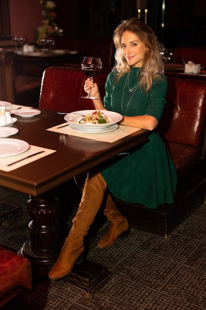 Hermosa mujer joven en la mesa con una copa de vino tinto