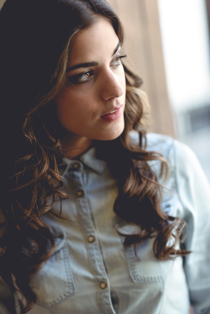 Hermosa mujer joven mirando por la ventana