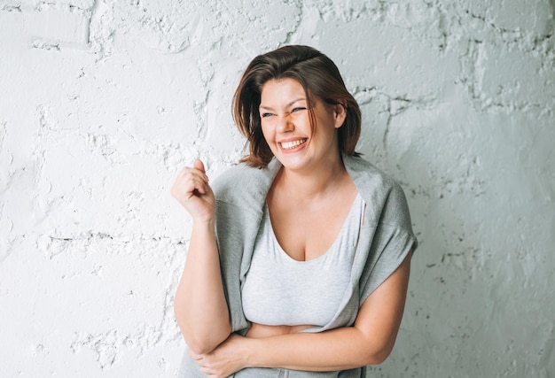 Foto hermosa mujer joven morena emocional feliz cuerpo de talla grande positivo en ropa deportiva cómoda