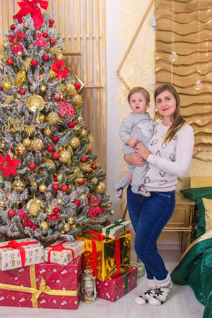 hermosa mujer joven con un niño pequeño cerca del árbol de navidad en navidad
