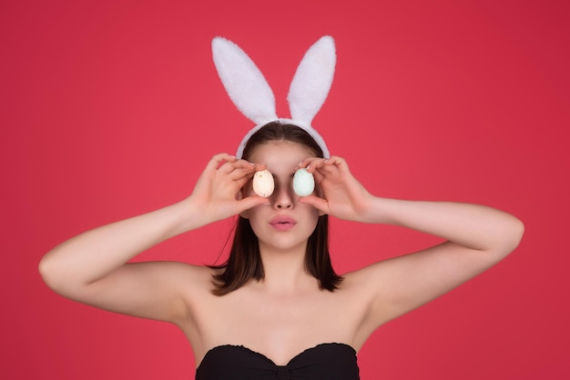 Hermosa mujer joven con orejas de conejo y huevos de pascua en el fondo del estudio conejito festivo y pascua