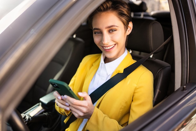 Hermosa mujer joven con el pelo corto conduce un coche en la ciudad