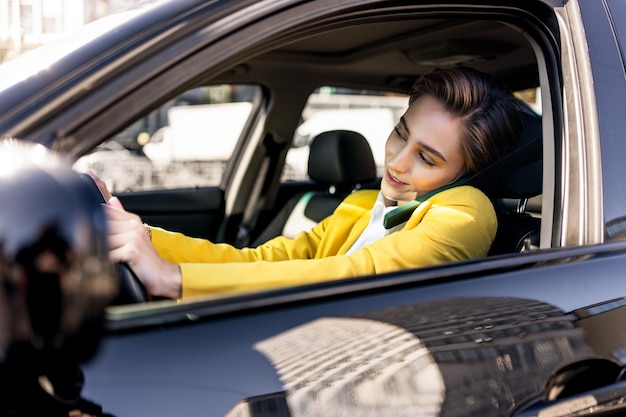 Hermosa mujer joven con el pelo corto conduce un coche en la ciudad