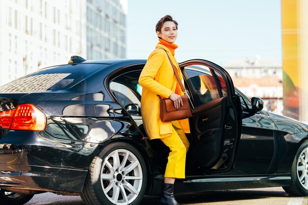 Hermosa mujer joven con el pelo corto conduce un coche en la ciudad