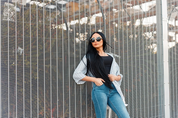 Hermosa mujer joven con pelo largo y negro en gafas de sol redondas de moda