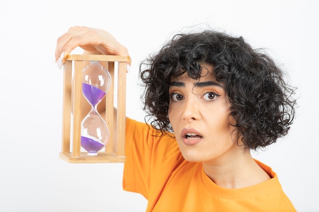 Foto hermosa mujer joven con pelo rizado con reloj de arena.