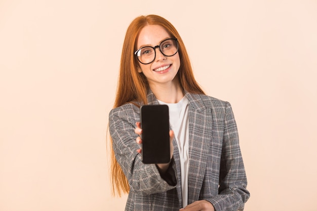 Hermosa mujer joven con pelo rojo en una chaqueta sobre un fondo beige