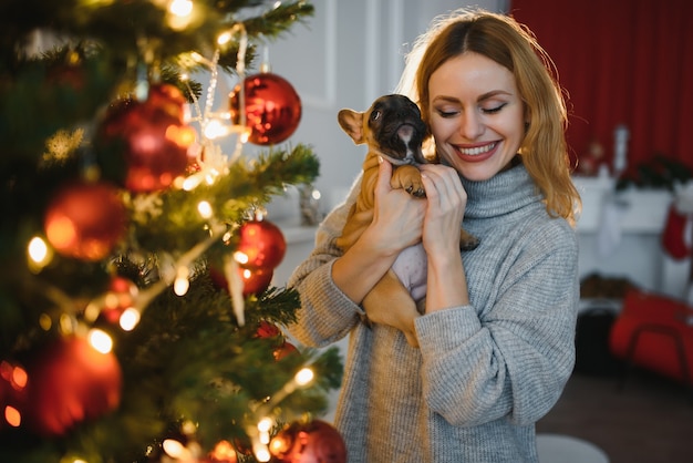 Hermosa mujer joven con un perrito en el fondo de la celebración de la Navidad