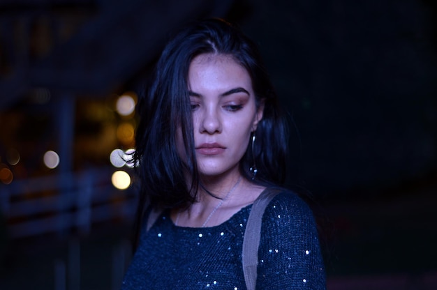 Foto una hermosa mujer joven de pie al aire libre por la noche