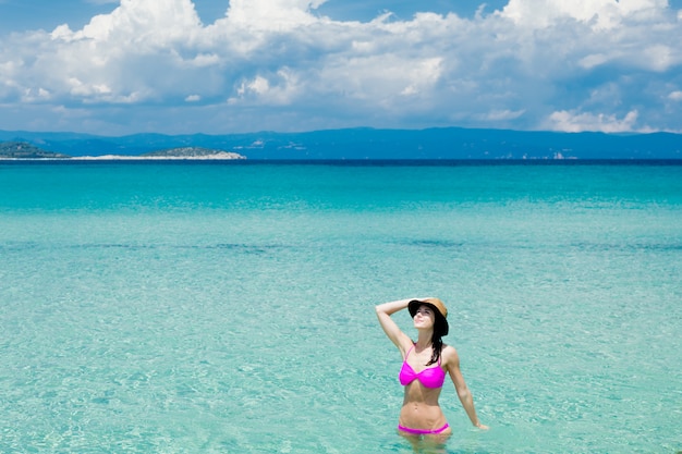 Hermosa mujer joven de pie en el maravilloso mar limpio en Grecia