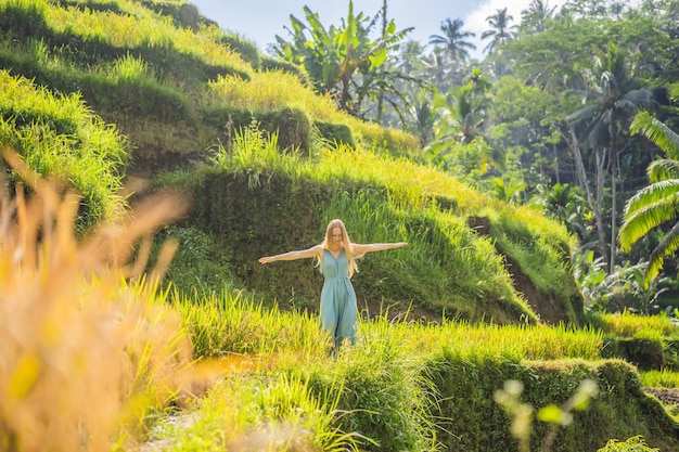 Hermosa mujer joven a pie en la típica ladera asiática con el cultivo de arroz en forma de montaña cascada verde campo de arroz terrazas arrozales Ubud Bali Indonesia Bali concepto de viaje