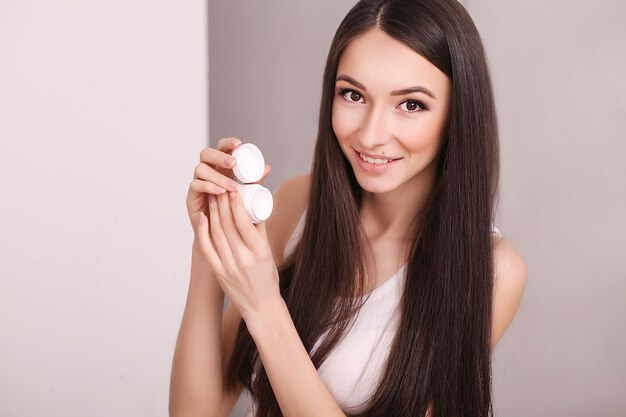 Hermosa mujer joven con piel limpia y fresca toca su cara