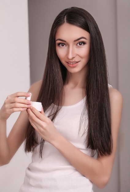 Hermosa mujer joven con la piel limpia y fresca toque la cara. Tratamiento facial, cosmetología, belleza y spa.