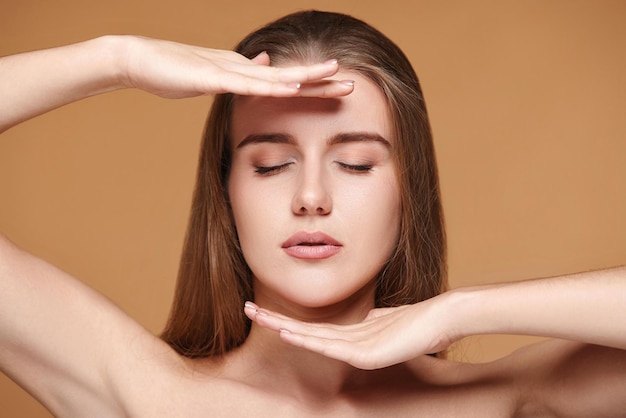 Hermosa mujer joven con piel perfecta revisa la línea de la frente y la barbilla