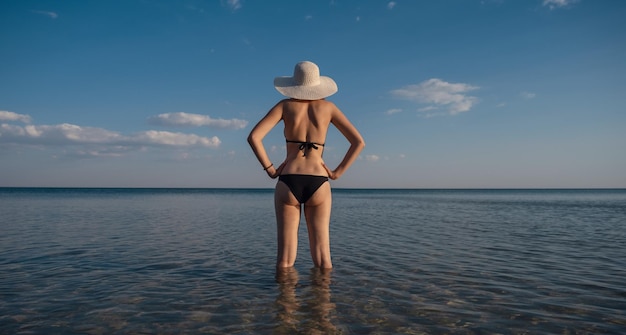 Hermosa mujer joven en la playa con sombrero