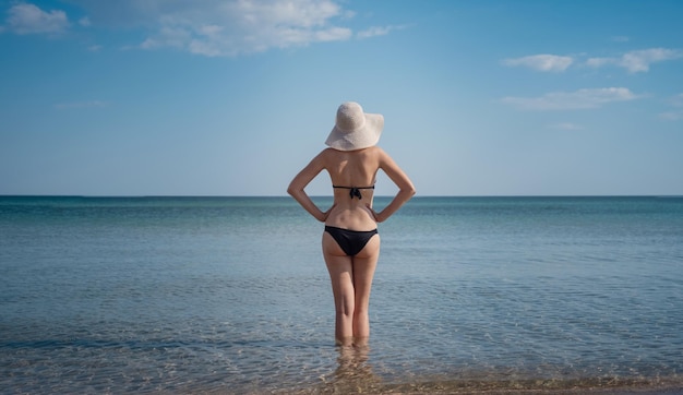 Hermosa mujer joven en la playa con sombrero