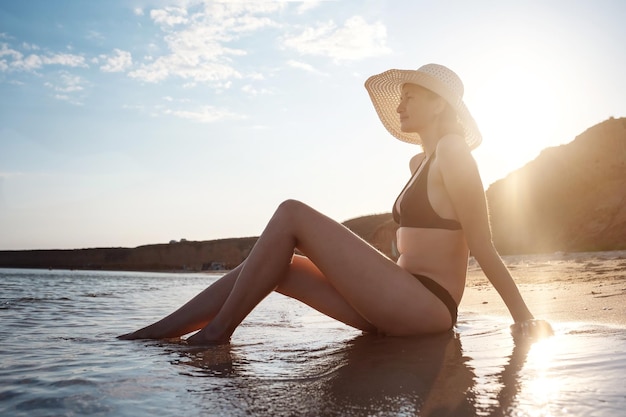 Hermosa mujer joven en la playa con sombrero