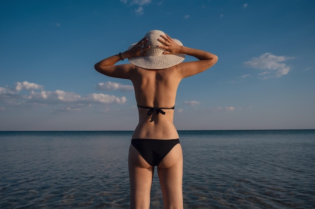 Hermosa mujer joven en la playa con sombrero