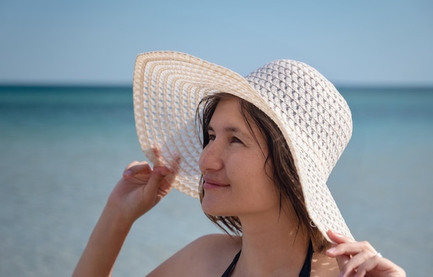 Hermosa mujer joven en la playa con sombrero