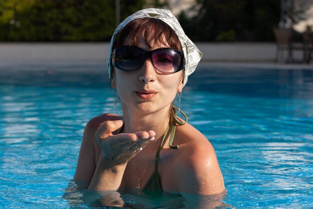 Hermosa mujer joven posando en la piscina en el resort mediterráneo en un hermoso día soleado de verano