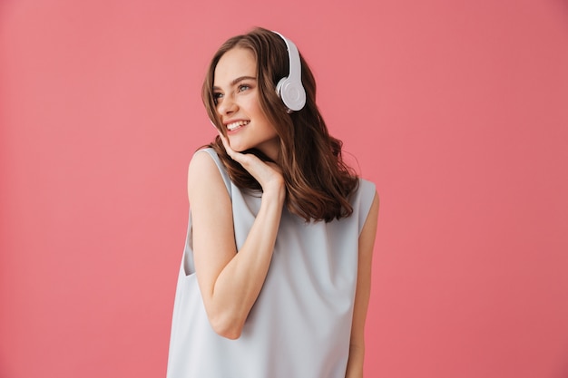 Hermosa mujer joven positiva escuchando música. Mirando a un lado.