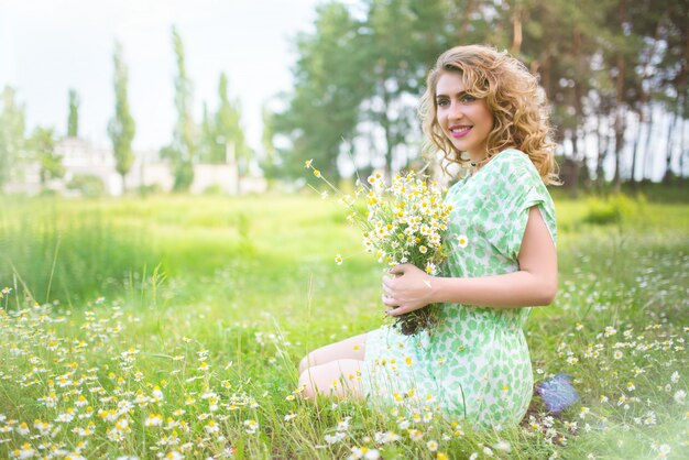 Hermosa mujer joven positiva en un vestido verde