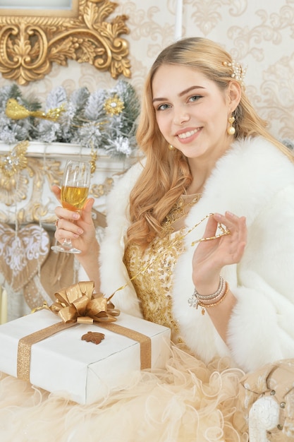 Hermosa mujer joven con presente en habitación decorada para vacaciones de Navidad