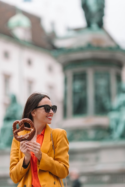 Hermosa mujer joven con pretzel y relajarse en el parque