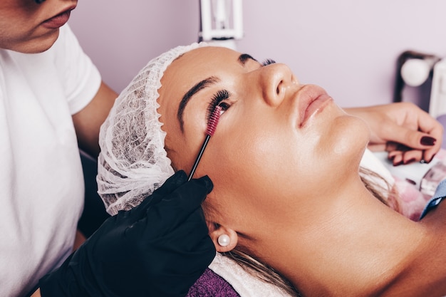 Hermosa mujer joven en el procedimiento de extensión de pestañas. Concepto de cosmética y cuidado corporal.