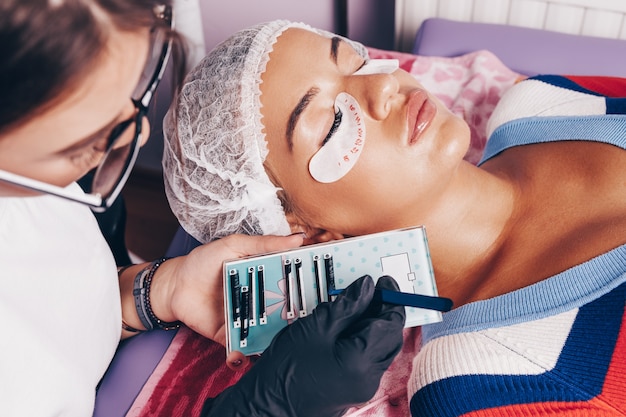 Hermosa mujer joven en el procedimiento de extensión de pestañas. Concepto de cosmética y cuidado corporal.