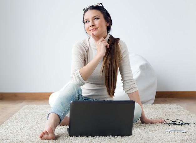 Hermosa mujer joven que trabaja en su computadora portátil en casa.