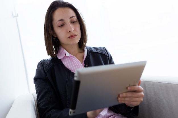 Hermosa mujer joven que usa su tableta digital en la oficina.