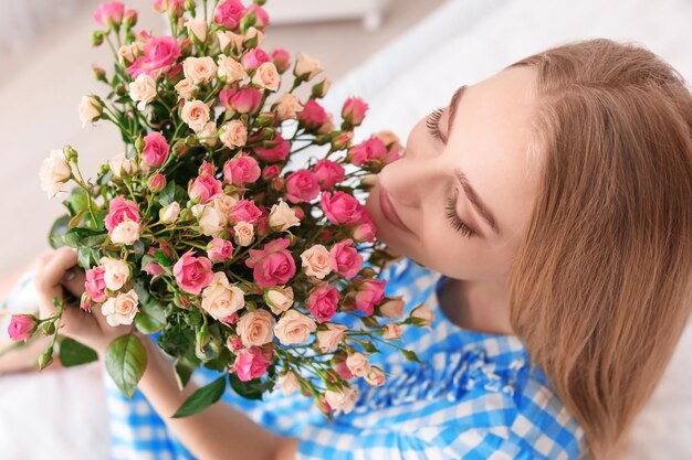 Hermosa mujer joven con ramo de rosas en el interior