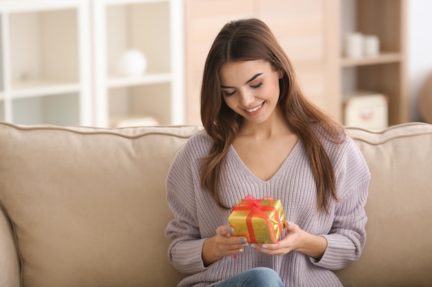 Hermosa mujer joven con regalo para el Día de San Valentín en casa