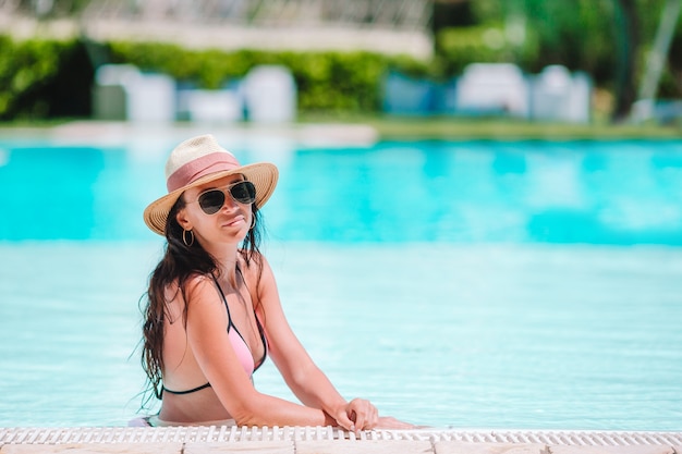 Hermosa mujer joven relajante en la piscina.