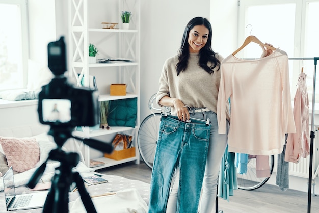 Hermosa mujer joven en ropa casual haciendo videos de redes sociales mientras pasa tiempo en casa