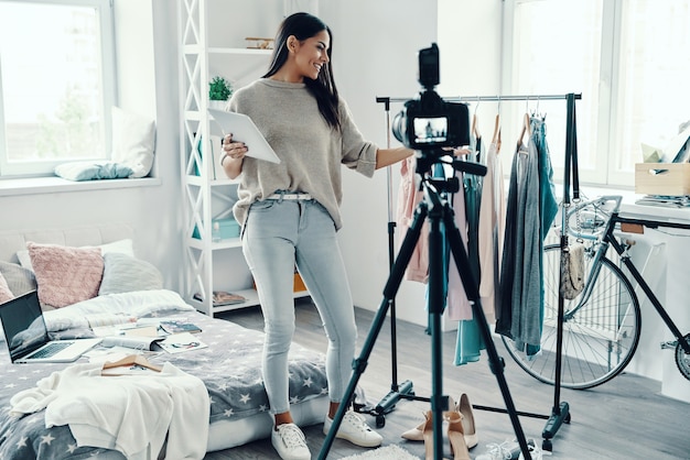 Hermosa mujer joven en ropa casual haciendo videos de redes sociales mientras pasa tiempo en casa