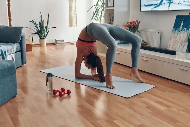 Hermosa mujer joven en ropa deportiva haciendo ejercicio en casa