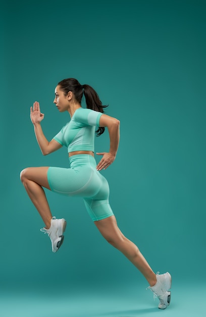 Hermosa mujer joven en ropa deportiva saltando en el aire