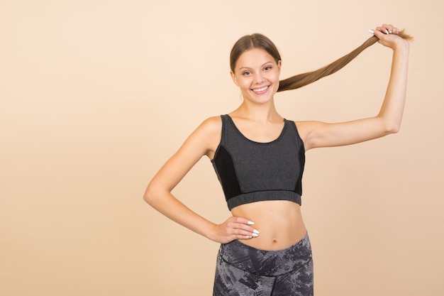 Hermosa mujer joven en ropa deportiva sobre un fondo beige