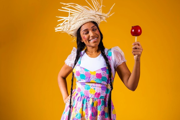 Hermosa mujer joven en ropa de fiesta de junio comiendo postre Love Apple Apple cubierto de caramelo rojo