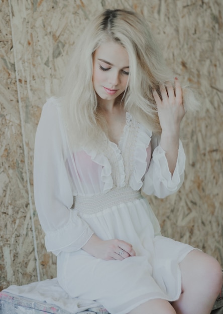 Hermosa mujer joven rubia con estilo en un vestido de encaje blanco de moda