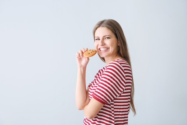 Hermosa mujer joven con sabrosa galleta en gris