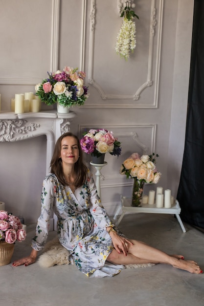 Hermosa mujer joven sentada en una habitación entre las flores