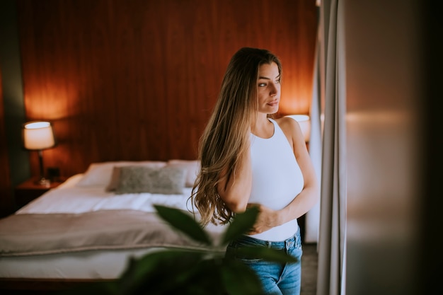 Hermosa mujer joven sentada junto a la ventana