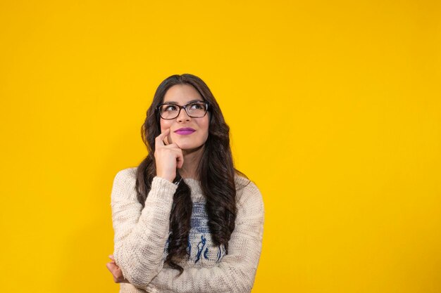 hermosa mujer joven sobre fondo amarillo aislado que tiene una buena idea mujer joven pensando en usar