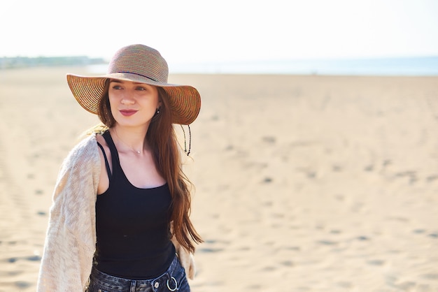 Hermosa mujer joven en sombrero de paja en la playa